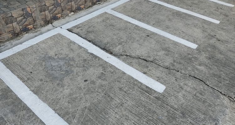 A parking lot with visible cracks in the concrete surface, highlighting the need for repair or maintenance.