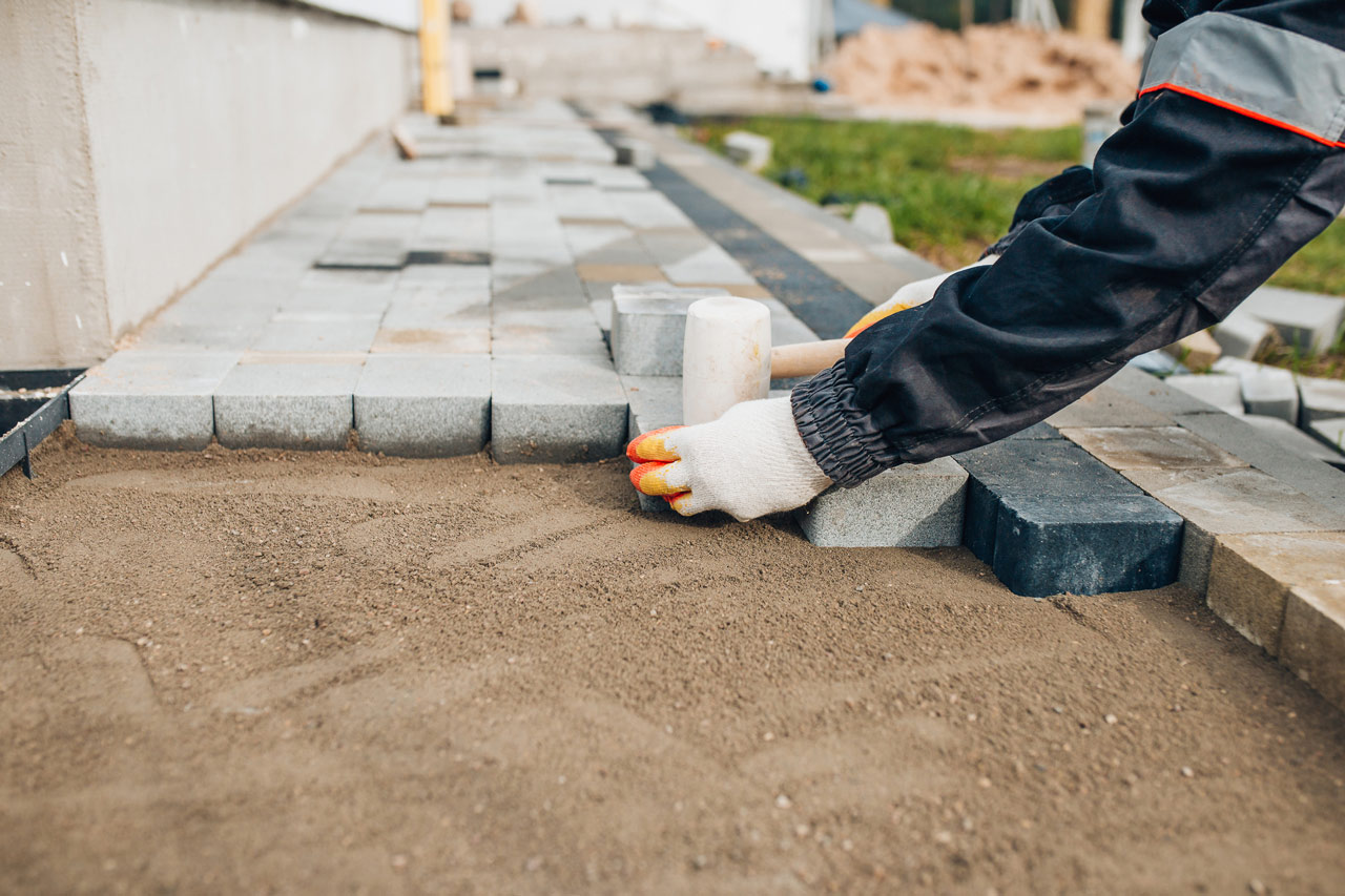 Skilled hands laying pavers to create a durable and aesthetically pleasing walkway or patio.