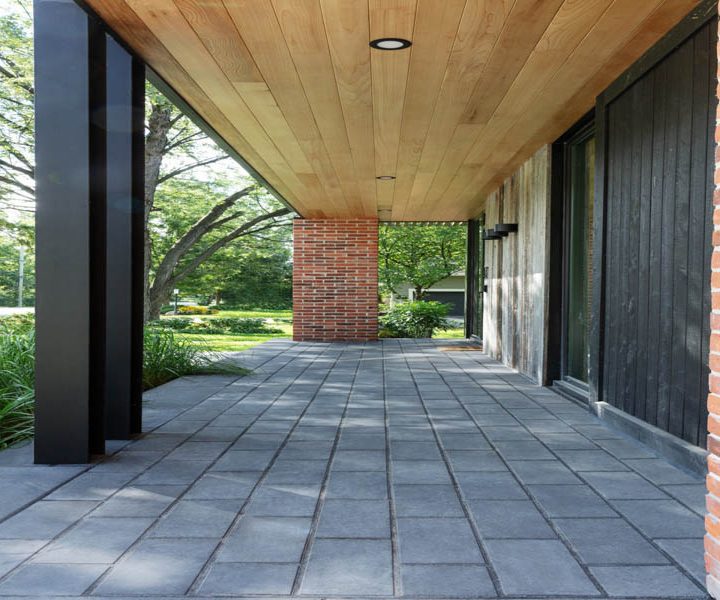 A sophisticated covered patio featuring brick accents and a wooden ceiling, perfect for outdoor relaxation.